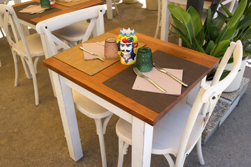 Colorful table setting with decorative items and utensils in a cozy outdoor dining area with plants