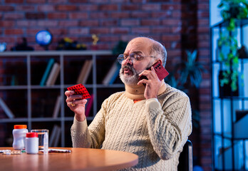 Old Indian man with medication calling doctor from home for health-related query