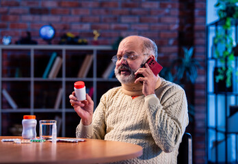 Old Indian man with medication calling doctor from home for health-related query