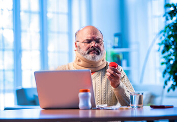 Elderly Asian man researching medicine dosage online at home using laptop