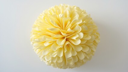 A decorative pom-pom with soft, ruffled layers in shades of yellow and cream.