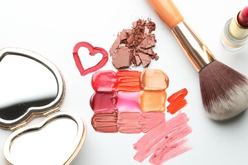Different cosmetic products, mirror and makeup brush on white background, flat lay