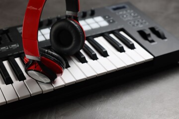 MIDI keyboard and headphones on grey table, closeup