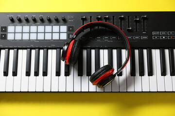 MIDI keyboard with headphones on yellow background, top view