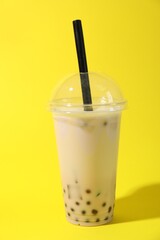 Tasty milk bubble tea in plastic cup on yellow background