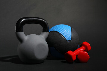 Medicine ball, dumbbells and kettlebell on black background