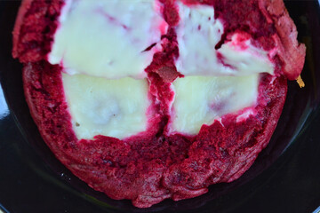 A close-up reveals the rich texture of a red velvet cake roll, generously filled and topped with creamy white frosting, hinting at its deliciousness