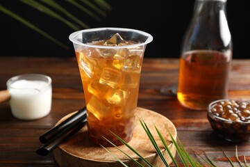 Tasty iced bubble tea and ingredients on wooden table