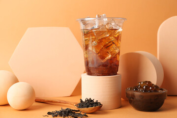 Tasty iced bubble tea and ingredients on orange background