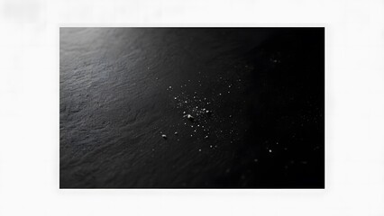 Scattered white particles on a dark, smooth surface