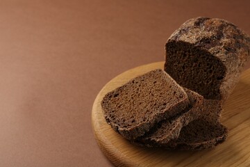 Pieces of fresh rye bread on brown background, closeup. Space for text