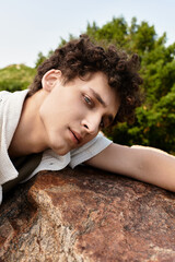 Stylish young man enjoys a sunny day in the park with vibrant greenery around