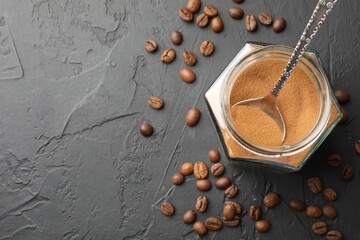 Instant coffee powder in jar and beans on dark textured table, flat lay. Space for text