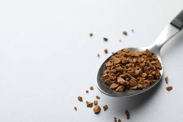 Spoon with granulated instant coffee on white background, closeup. Space for text