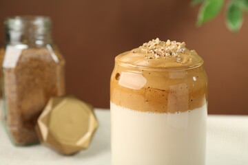 Delicious dalgona coffee in glass on blurred background, closeup. Space for text