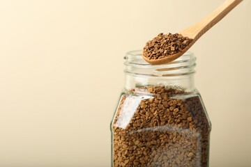 Taking instant coffee with spoon on beige background, closeup. Space for text