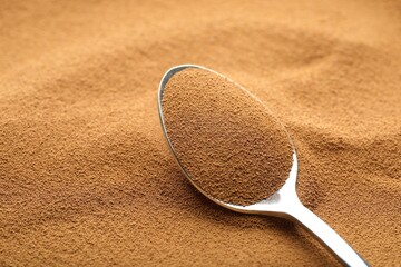 Spoon with aromatic instant coffee as background, closeup