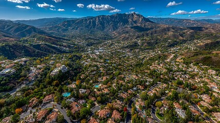Aerial View of Mountainous Suburban Neighborhood with Green Trees and Winding Streets Under Bright Blue Sky