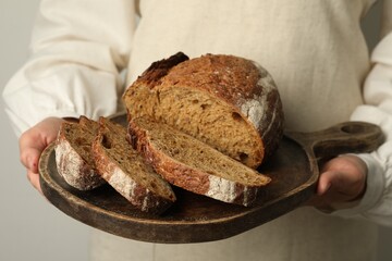 Woman with pieces of fresh bread on grey background, closeup