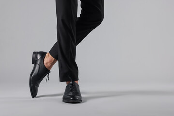 Man wearing pair of black leather shoes on light background, closeup. Space for text