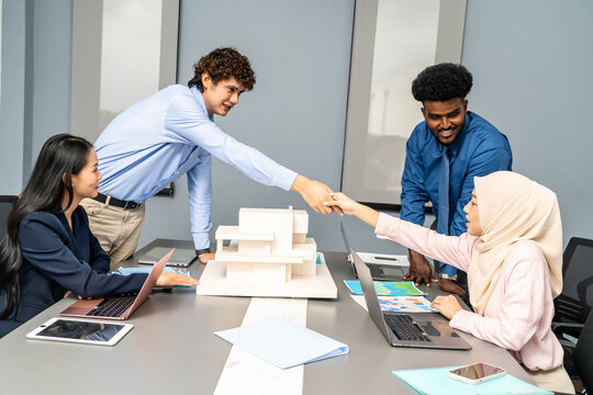 Architect engineer team shake hands and discussing about building construction projects. Group of diverse people working together to plan and design by using blueprint.