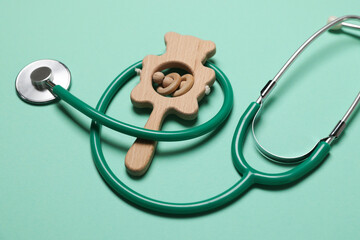 Pediatrics concept. Stethoscope and toy on turquoise background, closeup