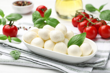 Tasty mozzarella cheese, tomatoes, basil and spices on white table, closeup