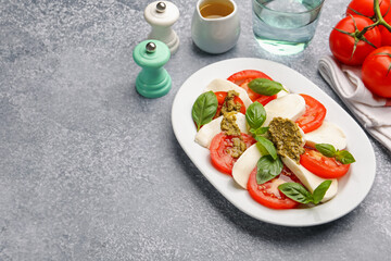 Tasty salad Caprese served with pesto sauce on grey table. Space for text