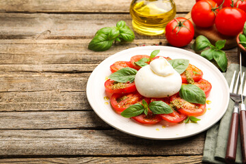 Tasty salad Caprese served with pesto sauce on wooden table, closeup. Space for text