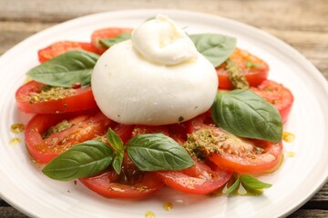 Tasty salad Caprese with mozzarella, tomatoes, basil and pesto sauce on table, closeup