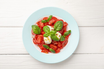 Tasty salad Caprese with mozzarella, tomatoes, basil and spices on white wooden table, top view