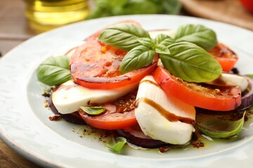Tasty salad Caprese with mozzarella, tomatoes, basil and spices on table, closeup