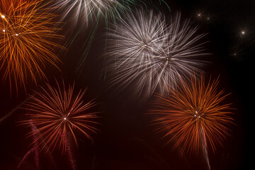 Bright white and orange fireworks lighting up the dark sky during a nighttime celebration or public event