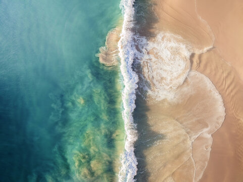 Aerial view of turquoise waters meet golden sands in a dynamic dance of contrasting hues and textures, Port Willunga, South Australia, Australia.