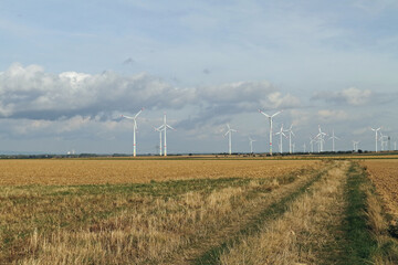 Wind turbines in an open field with cloudy sky in the background