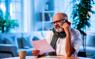 Elderly Indian man calls CA to talk about tax report while sitting at home table