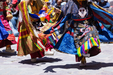 Masked performers in vibrant, flowing costumes dance energetically during the Hemis Festival in...