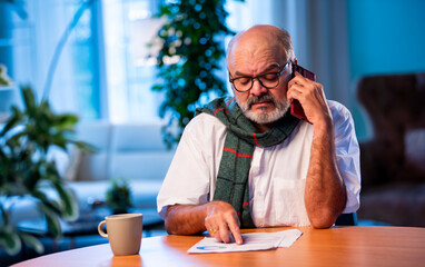 Elderly Indian man calls CA to talk about tax report while sitting at home table