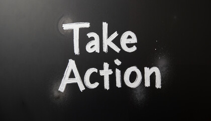 Handwriting motivational phrase 'Take Action' on blackboard background  