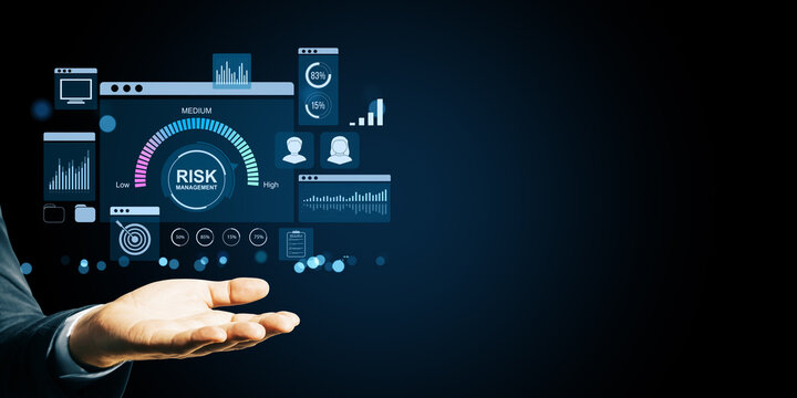 Businessman hand holding digital risk management dashboard interface with data analysis icons and financial graphs on dark background.