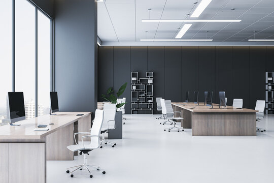 Modern spacious coworking office interior with wooden desks, white chairs, black walls, computers, and large windows in city building. 3D Rendering