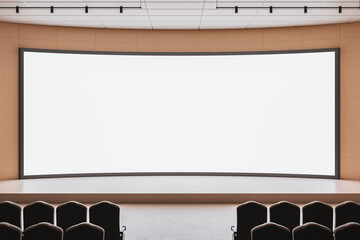Empty auditorium with large curved blank screen and stage prepared for conference or business...