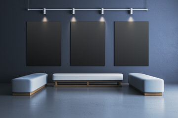 Three blank vertical black posters on dark wall with spotlights in modern gallery room with light...