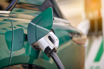 Closeup view of charger plug connected to green electric car charging port, eco transport and clean...