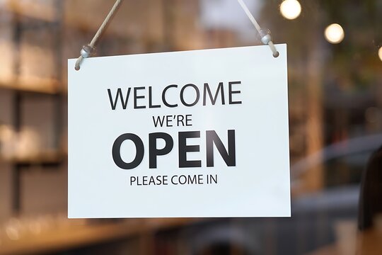 Welcome Were Open Sign Hanging on Glass Door of a Storefront Business Welcoming Customers