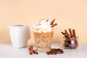 Iced cinnamon latte with whipped cream, cinnamon syrup and cinnamon powder on top, with coffee...