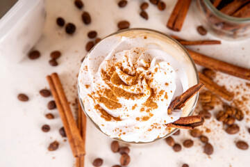 Iced cinnamon latte with whipped cream, cinnamon syrup and cinnamon powder on top, with coffee...