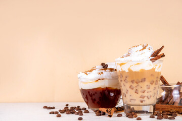 Iced cinnamon latte with whipped cream, cinnamon syrup and cinnamon powder on top, with coffee...
