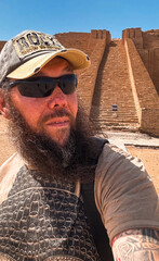 Tourist explores ancient ziggurat site in Iraq under clear blue skies