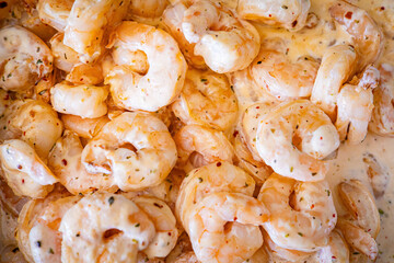 Shrimps background texture in white creamy sauce. A lot of shrimps horizontal banner background. Cooked shrimps.
